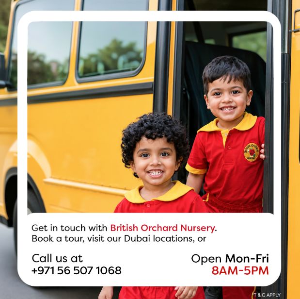 Two happy children in red uniforms smiling at the door of a yellow school bus.