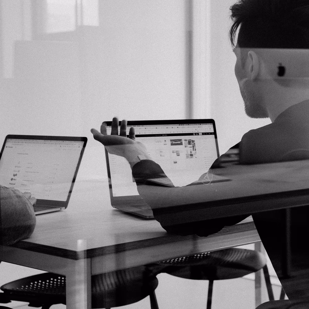 Black and White Image of Investment Professionals meeting with Service Providers discussing business while working on laptops.