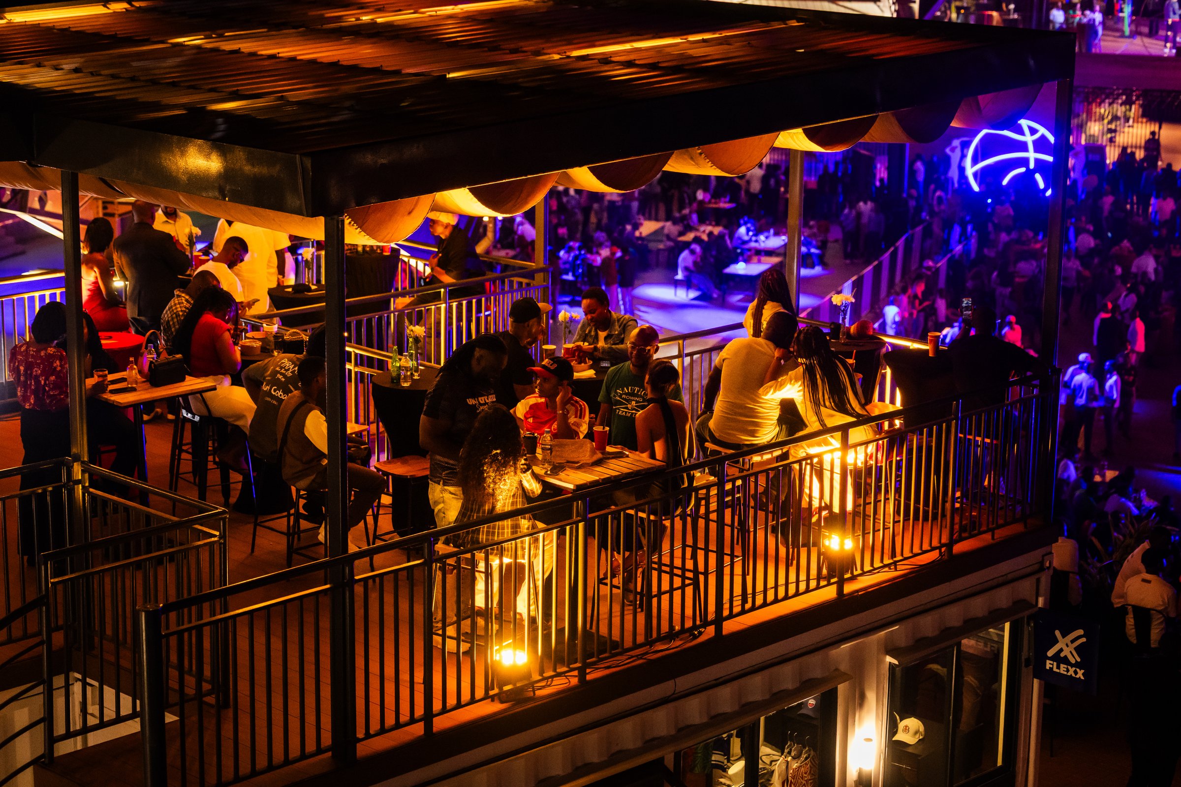 Guests on the sports bar balcony at Zaria Court Kigali at night