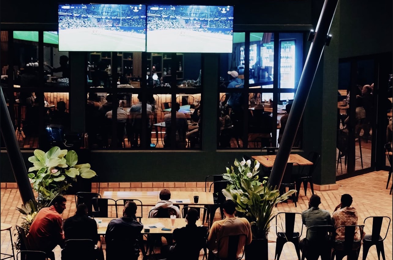 Outdoor terrace seating beneath the big screens at the Zaria Court Kigali sports bar at night