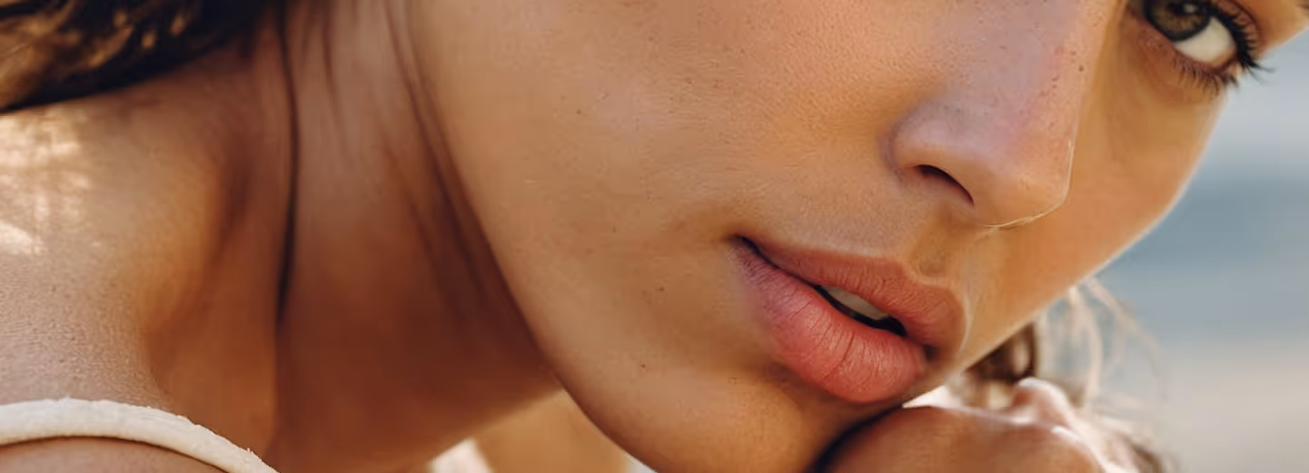 Close-up of a woman's face showing clear skin, freckles, and natural lips.