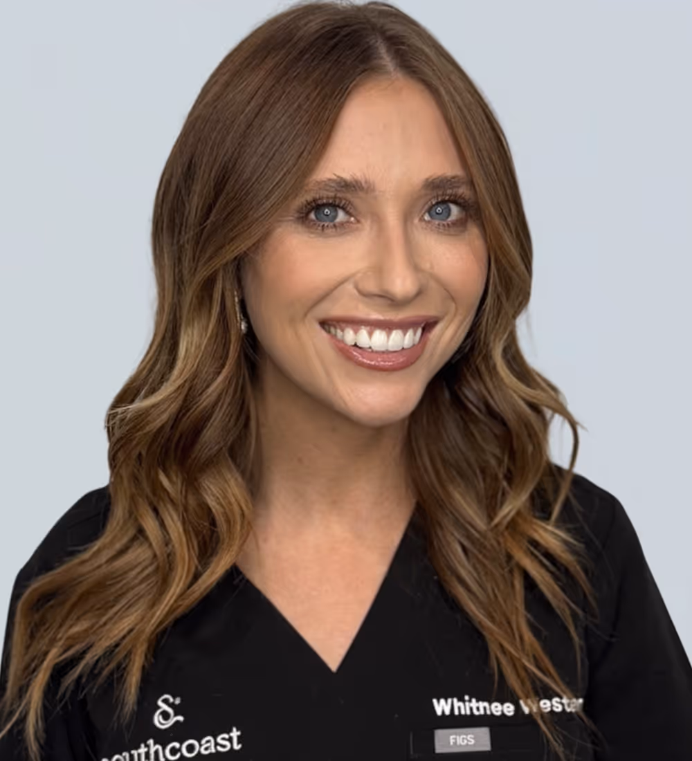 Smiling woman with wavy brown hair wearing a Southcoast uniform with name tag reading Whitnee Westcott.