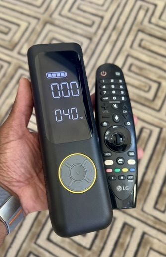 Fanttik X8 Apex held in one hand next to a TV remote for size comparison