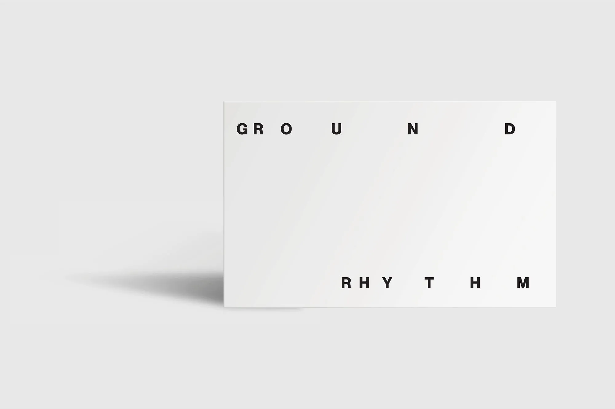 Minimalist mockup of a white book cover titled Ground Rhythm, with widely spaced black letters on a white background casting a soft shadow.
