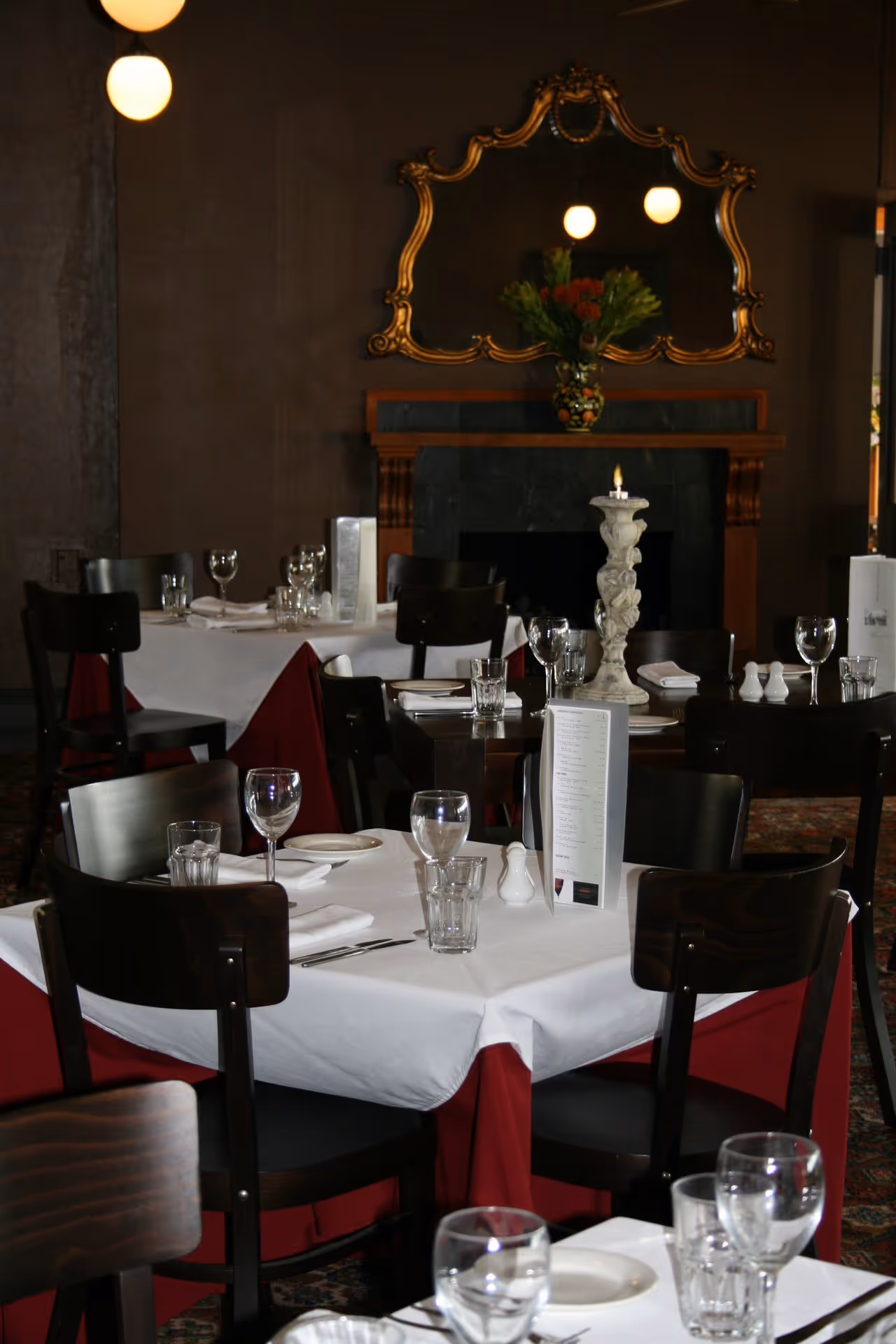 Elegant restaurant interior featuring neatly set tables with white tablecloths, glassware, and warm ambient lighting.