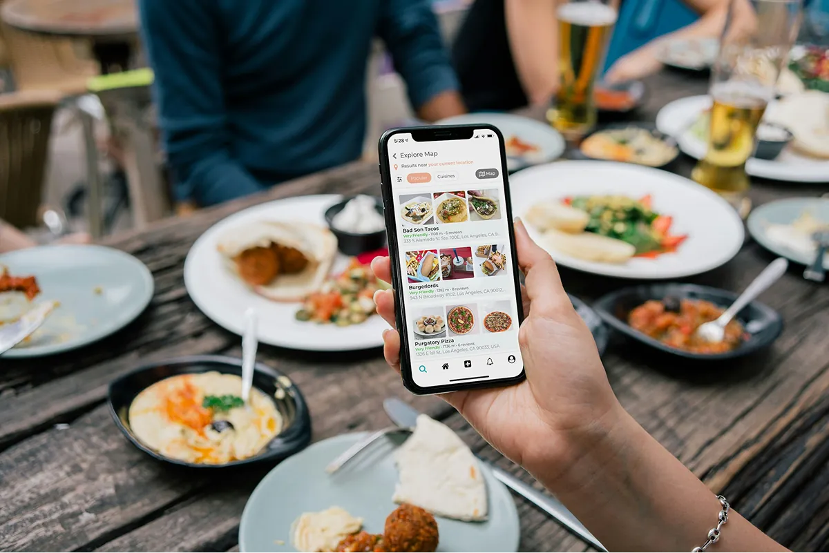 Diner holding a phone with a food delivery app over a table of dishes