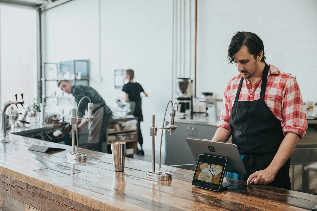 Restaurant worker using a point-of-sale tablet at the counter