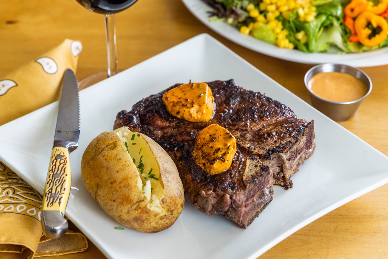 Juicy T-bone steak with baked potato and herb butter at the Broken Spur Steakhouse in Torrey, Utah