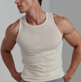 A close-up image of a muscular man wearing a light-colored tank top, showing confidence in a posed stance.