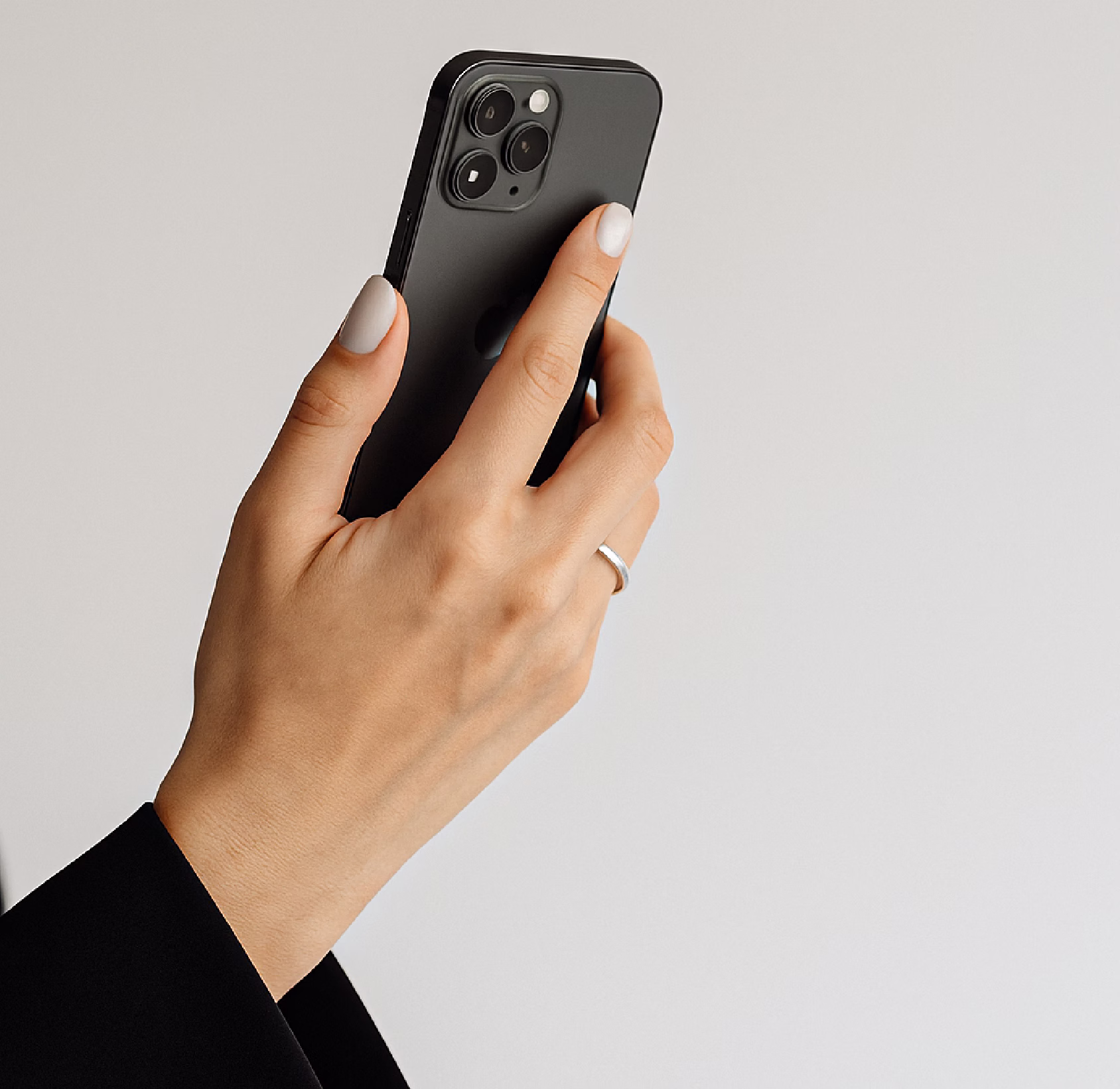 A hand holding a black smartphone with three rear camera lenses and the Apple logo visible.