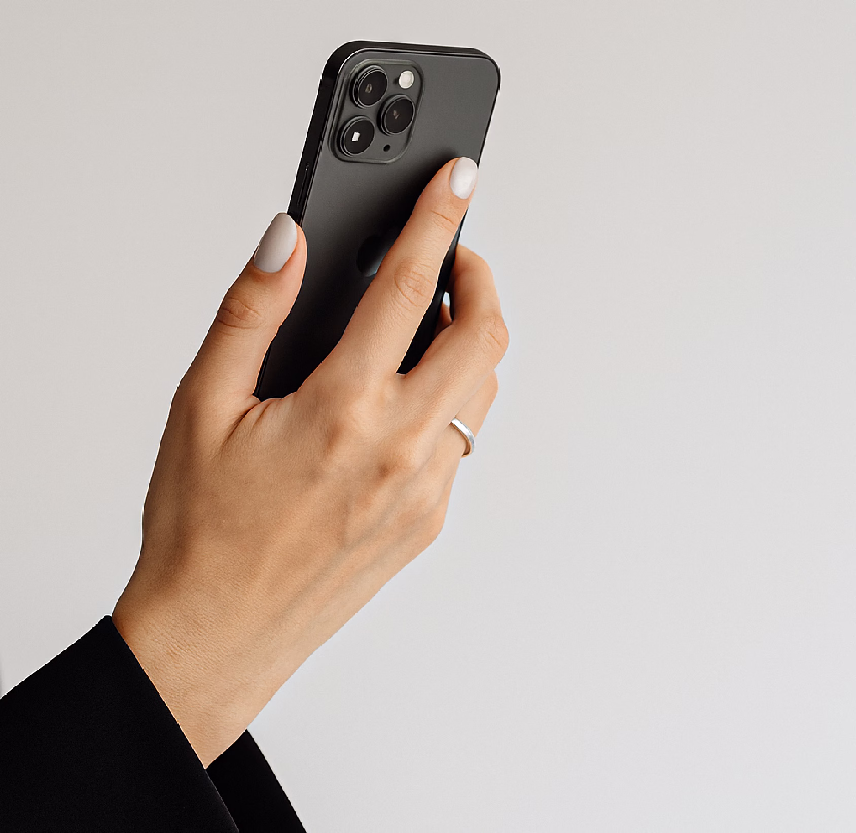 A person's hand holding a black smartphone with three rear camera lenses.