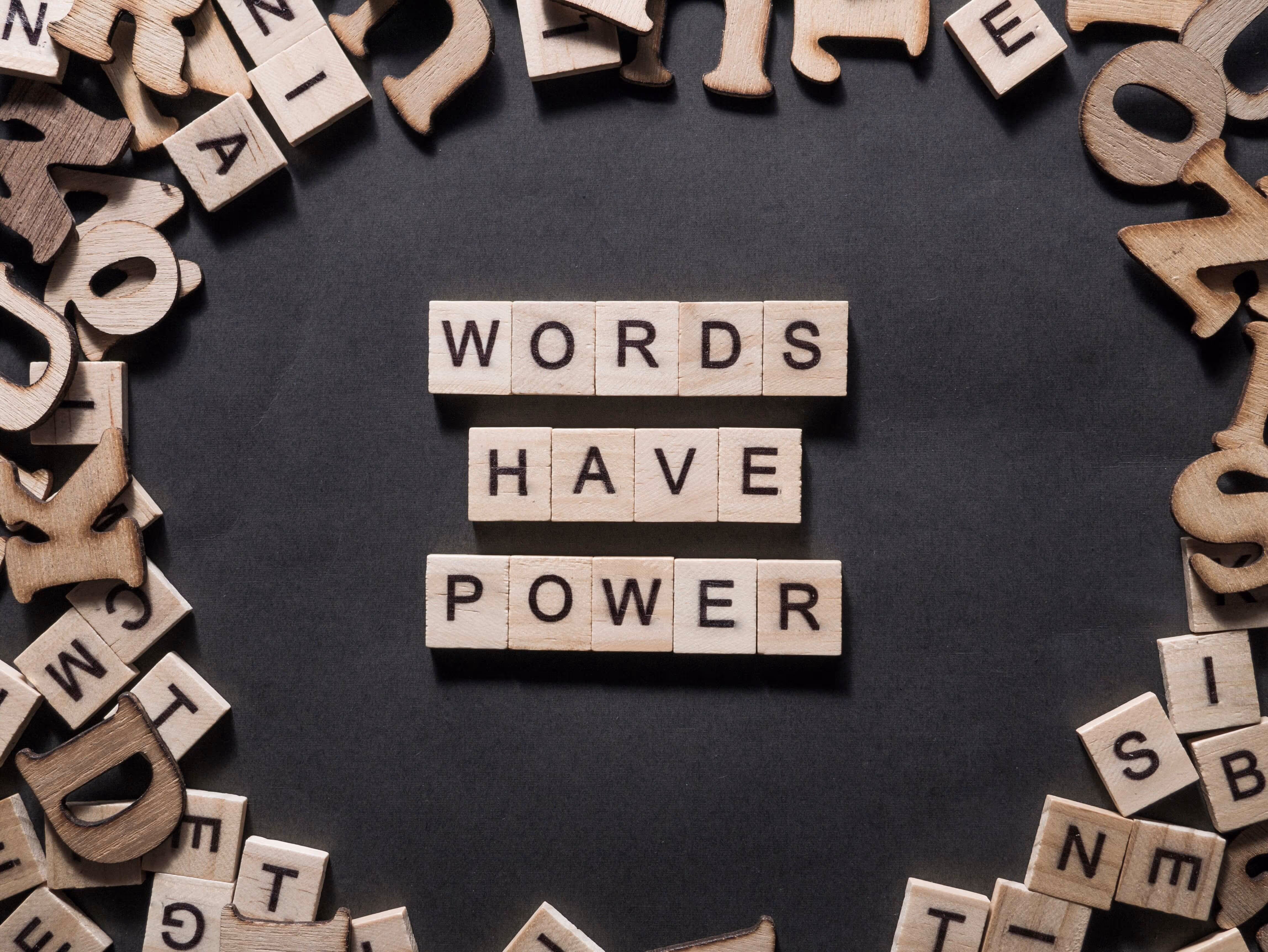 Holzbuchstaben bilden den Schriftzug „Words Have Power“ auf schwarzem Hintergrund – Symbol für professionelle Texterstellung