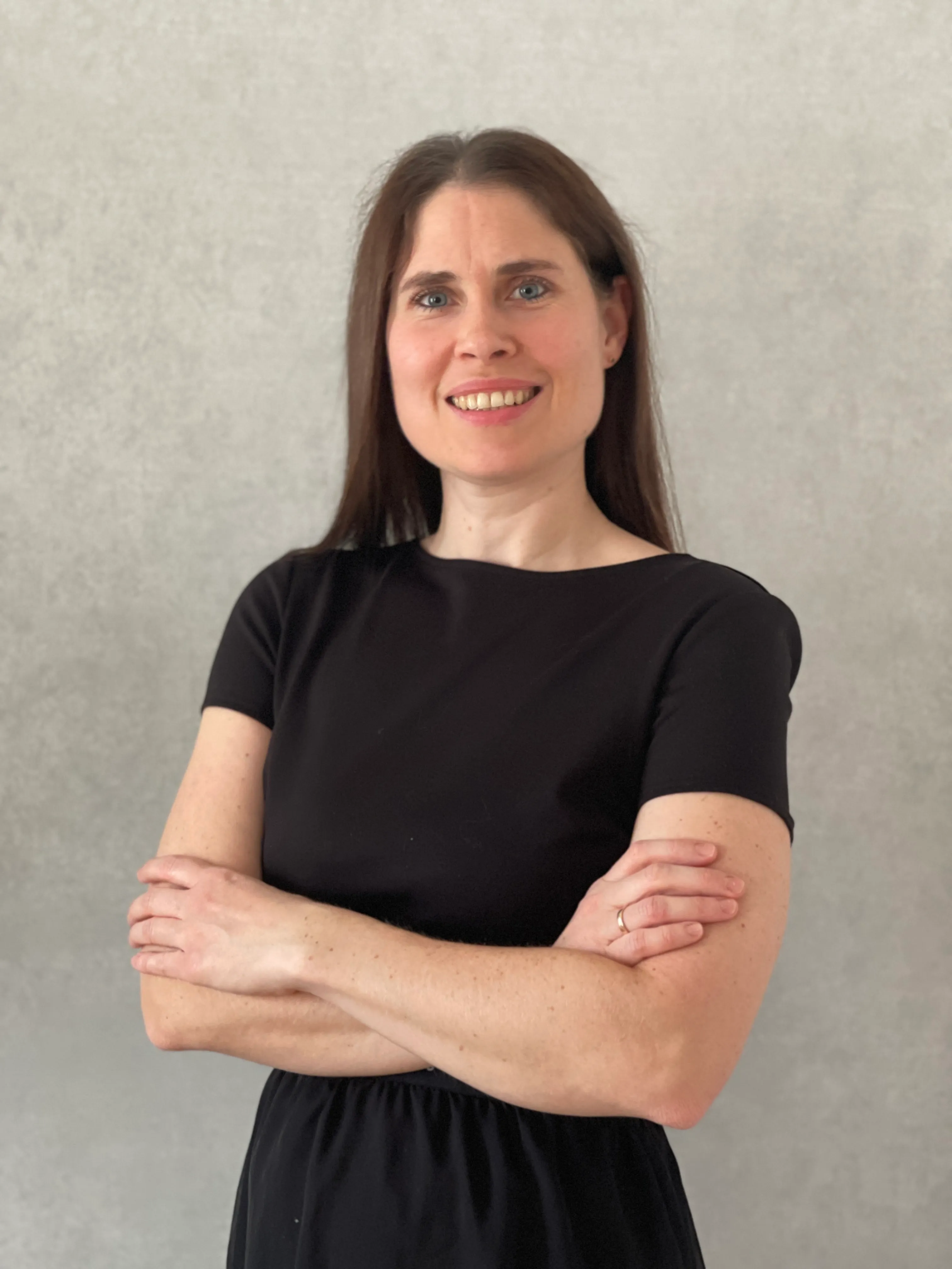 Portrait einer jungen Damit mit dunklen Haare und einen schwarzen Kleid mit einem natürlichen Lächeln