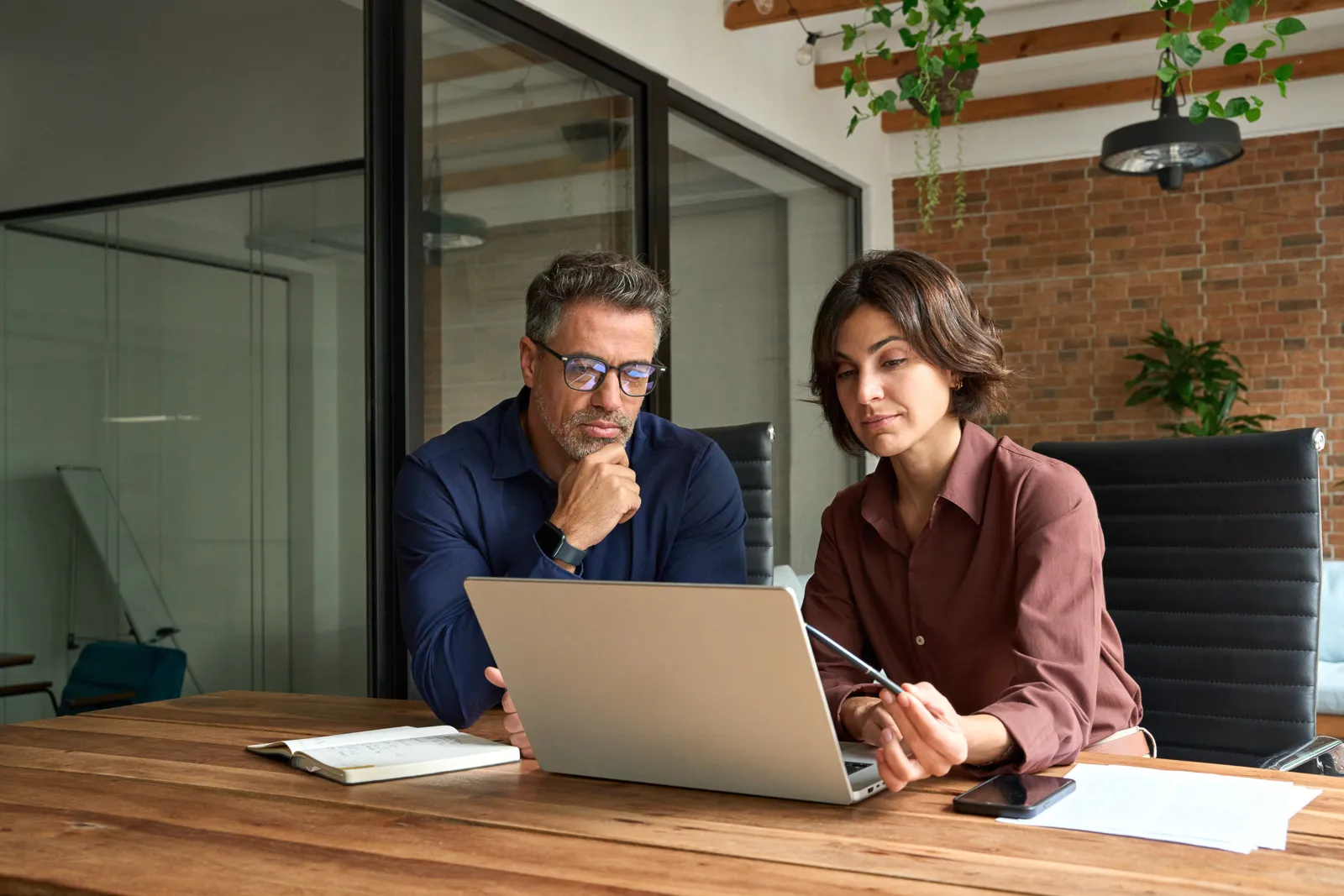 Business Meeting – Mann und Frau besprechen gemeinsam ein Projekt am Laptop in modernem Büro