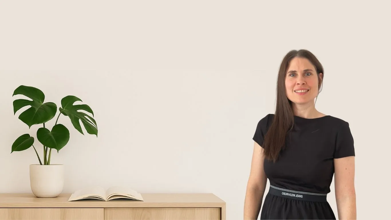 Porträt von Christina Stix-Pusswald vor hellem Hintergrund neben einer Monstera-Pflanze und offenem Buch.