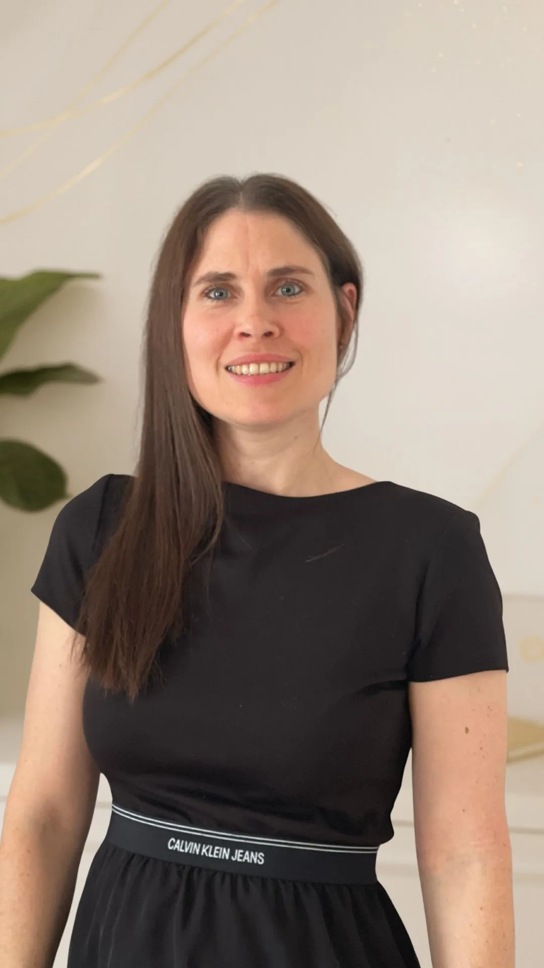 Christina Stix-Pusswald lächelt in die Kamera vor einem hellen Hintergrund mit goldenen Akzenten.