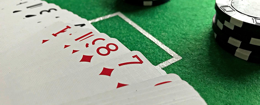 Close-up of playing cards spread out on a green felt table with poker chips nearby.