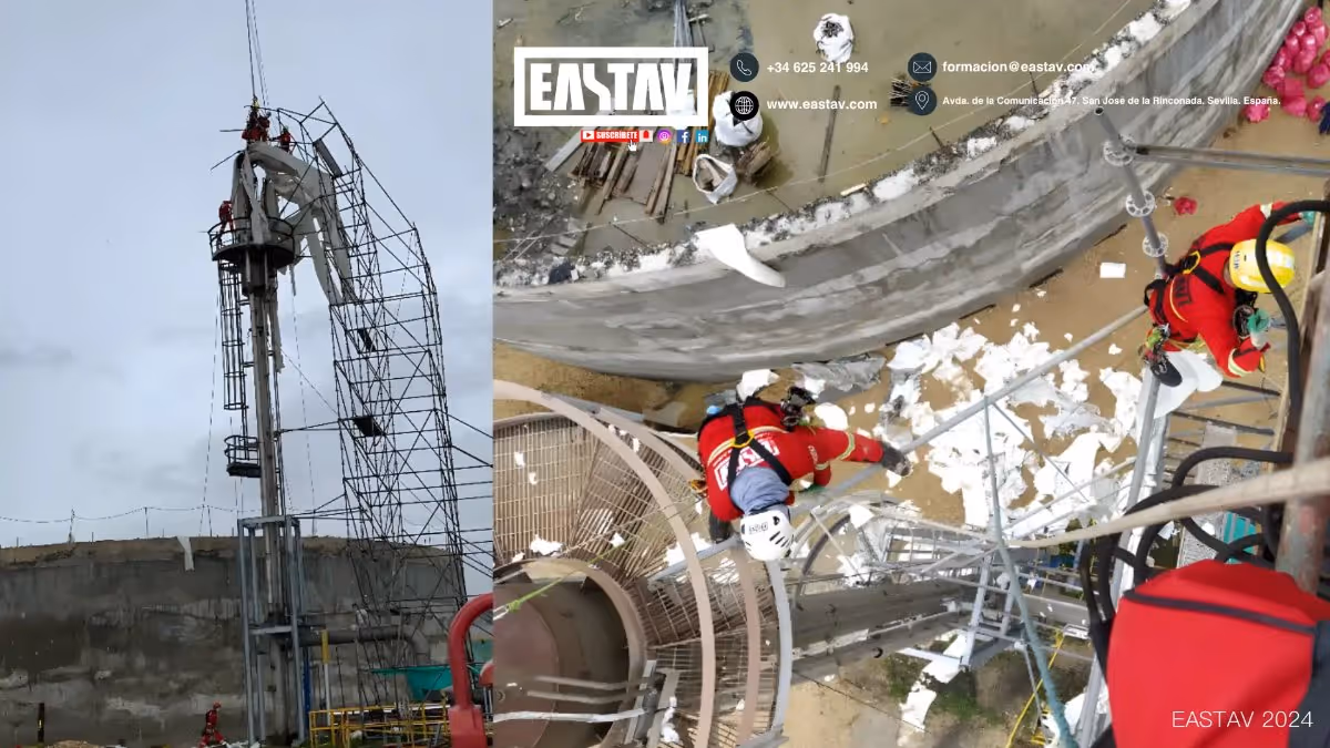 Técnicos de seguridad trabajando con arneses y casco en una estructura metálica alta en un sitio de construcción con andamios y materiales dispersos.