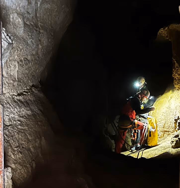 Exploradores de cuevas con equipo de seguridad y cascos con luces, investigando una caverna oscura.