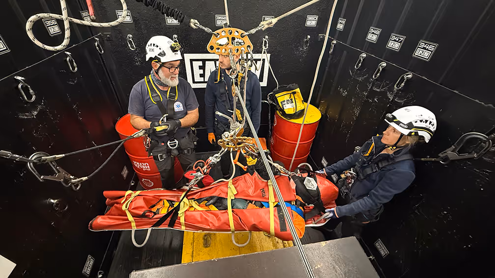 Equipo de rescate profesional preparando camilla roja para evacuación en ambiente industrial oscuro.