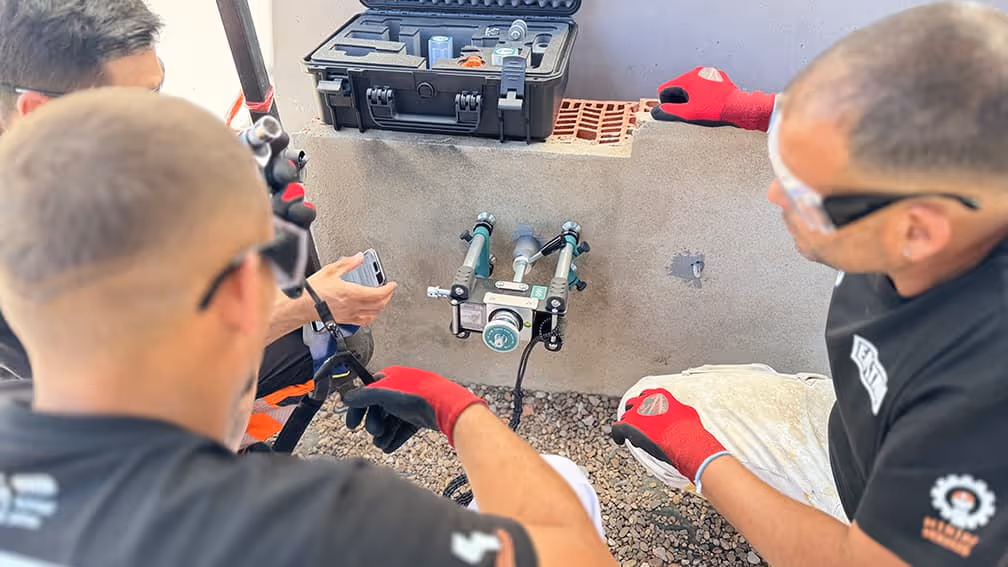 Técnicos inspeccionan componentes hidráulicos con herramientas y equipo profesional en el suelo.
