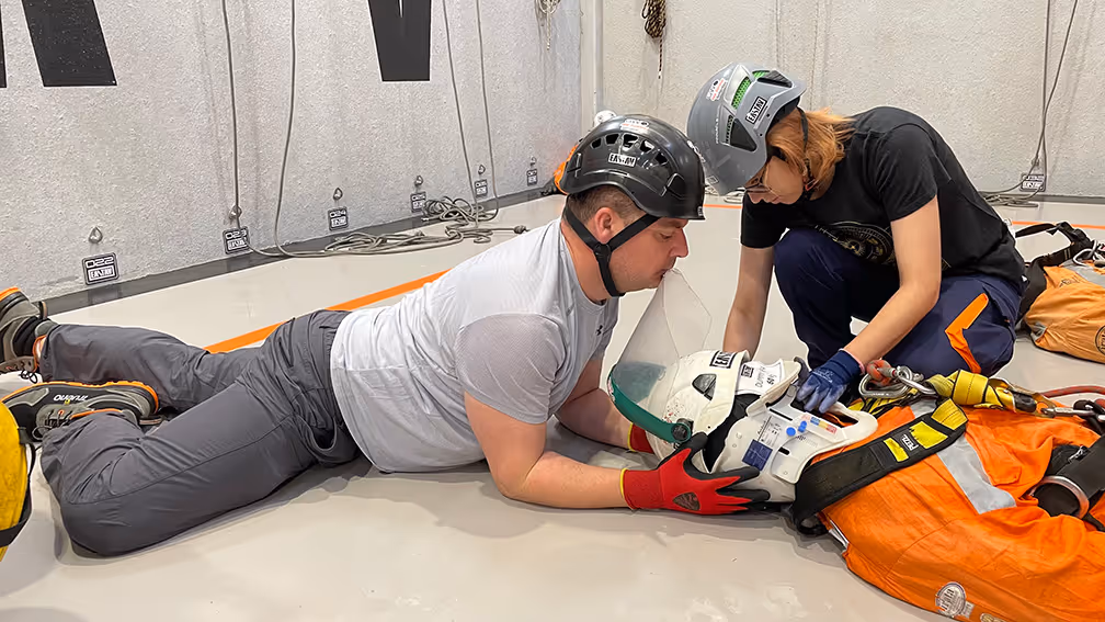 Instructor enseña a hombre en casco equipo de paracaidismo en túnel de viento.