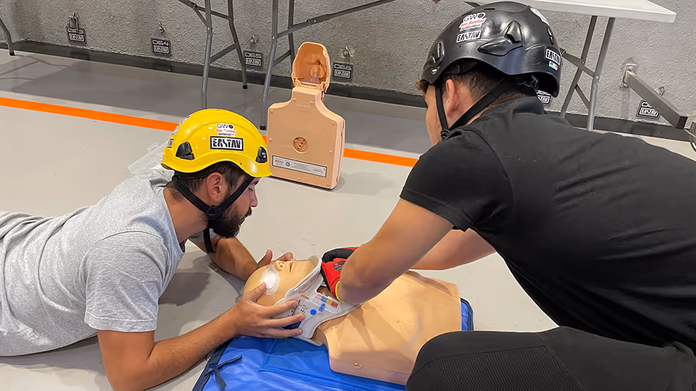 Dos instructores practicando técnicas de primeros auxilios y reanimación cardiopulmonar en maniquí.