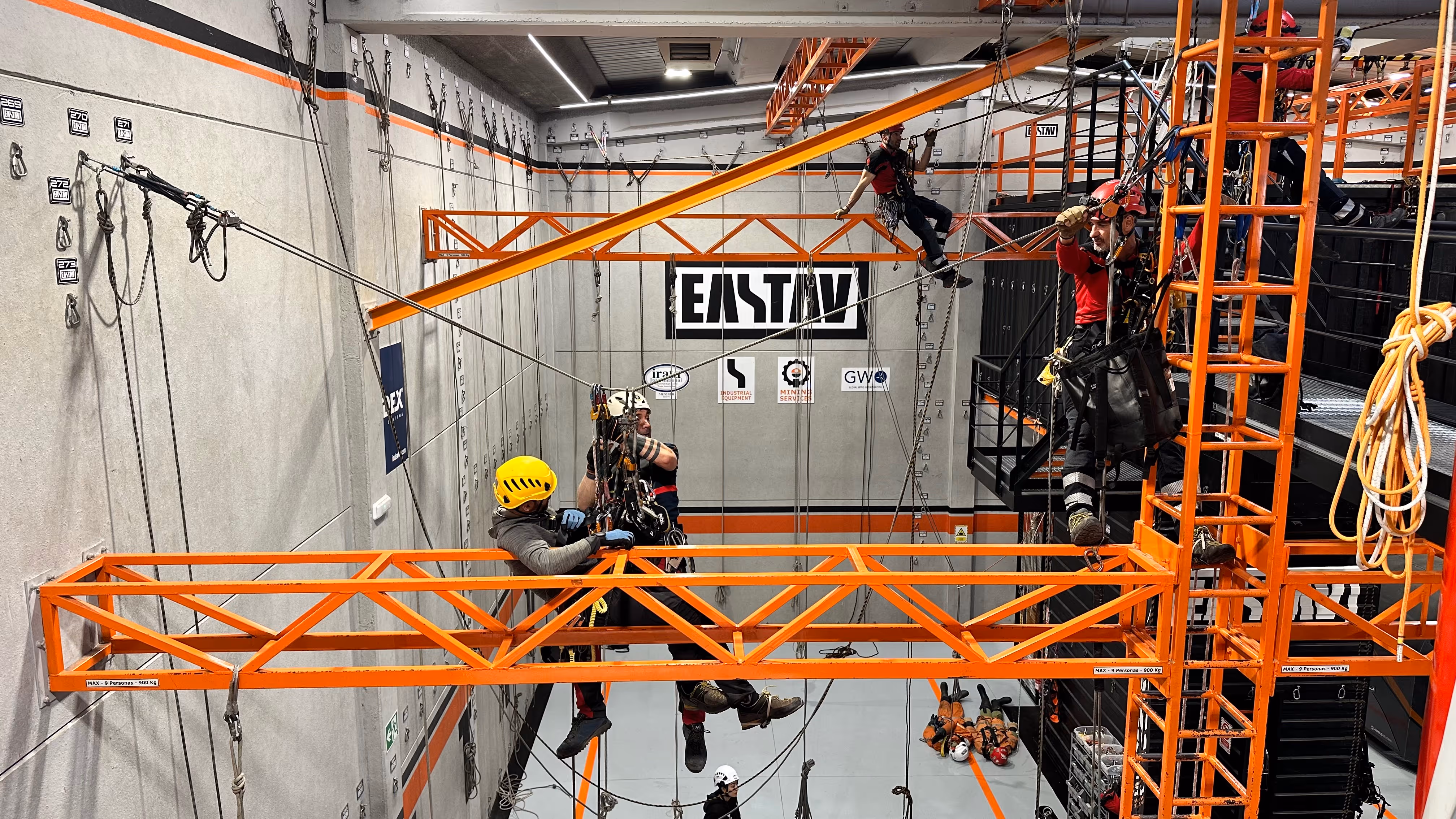 Trabajadores en entrenamiento de seguridad en altura usando arnés y equipo de protección.