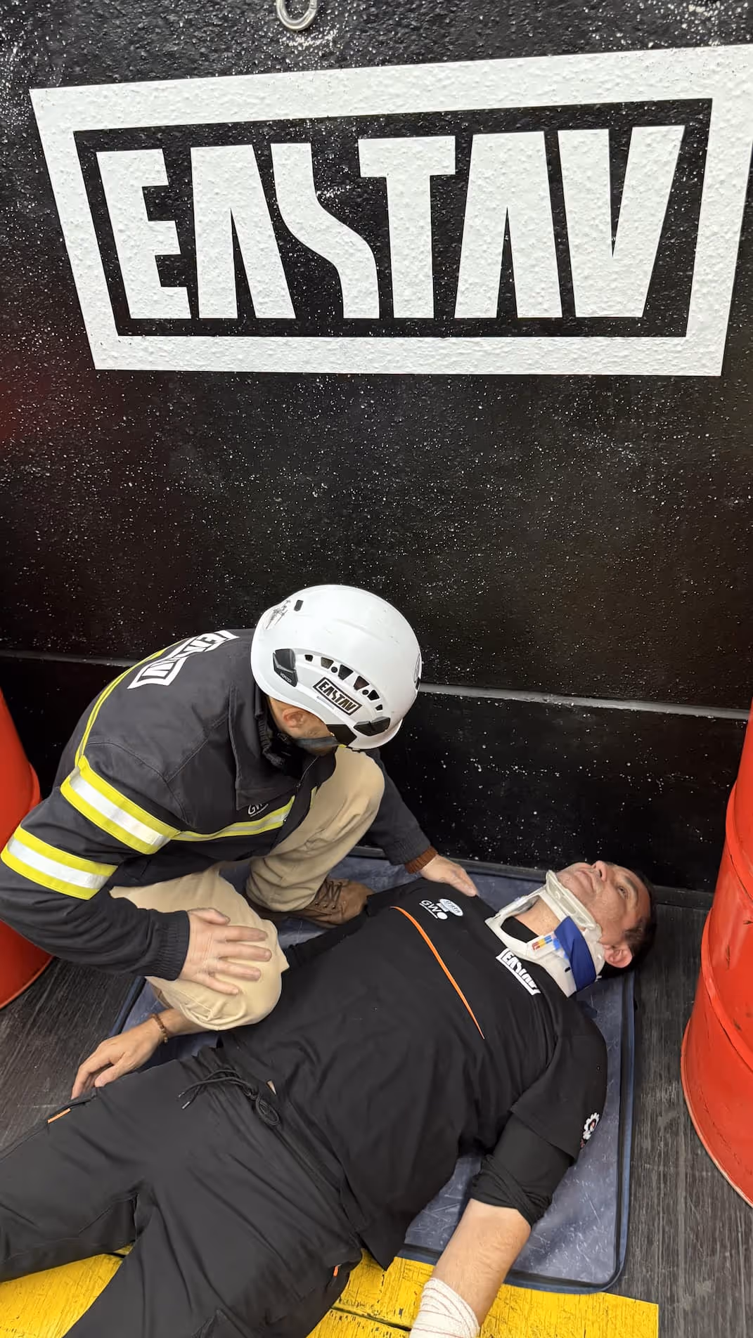 First aid responder assisting injured person in front of emergency vehicle