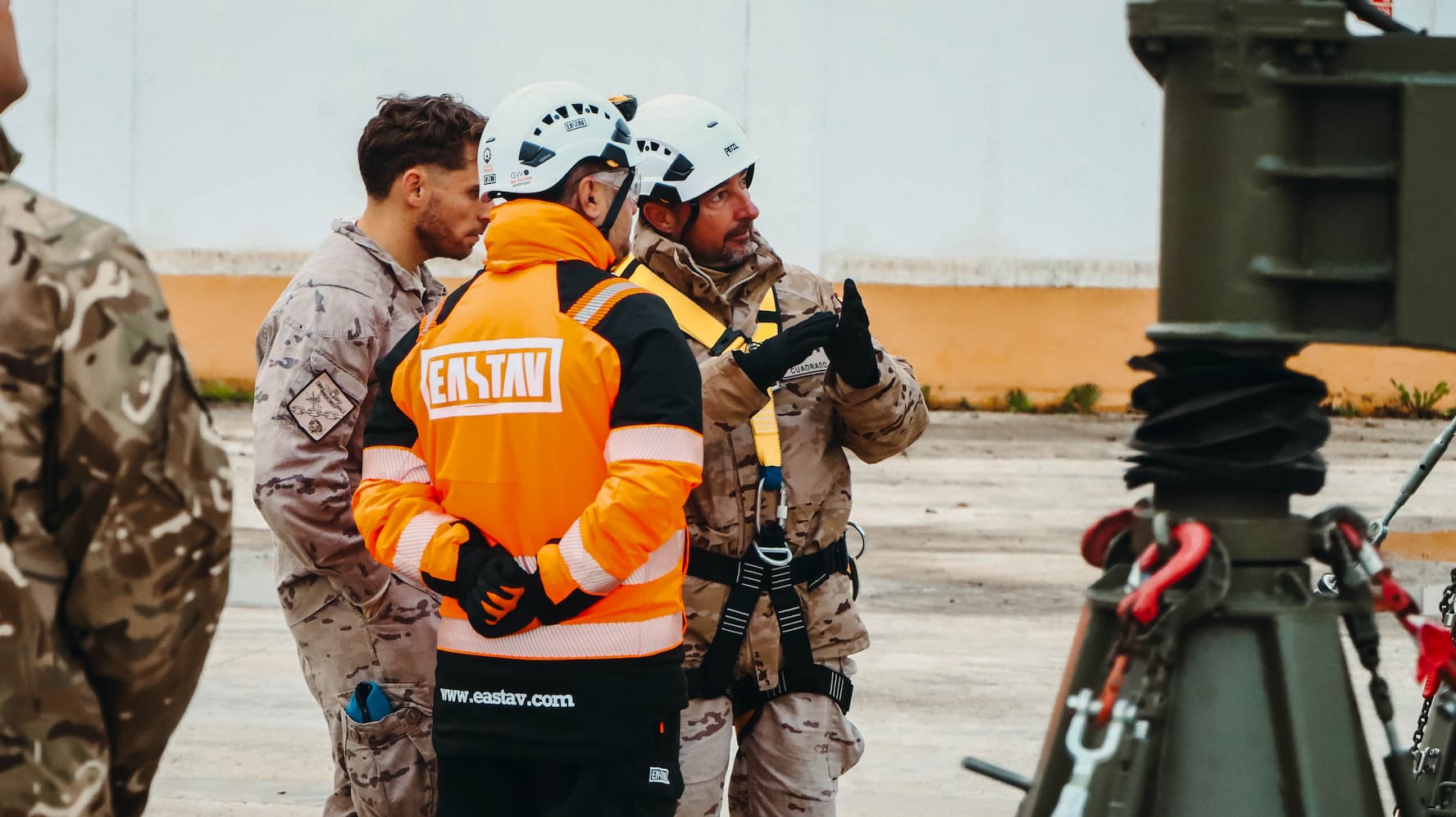 Equipo eastav en uniforme naranja y casco colaborando en operación de rescate militar.