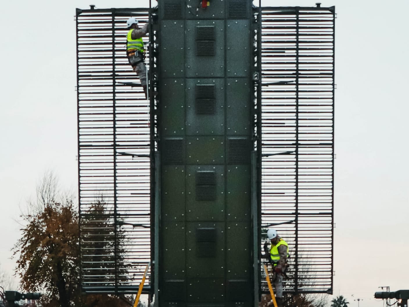 Trabajadores en chaleco de seguridad instalan equipos eastav en estructura metálica verde