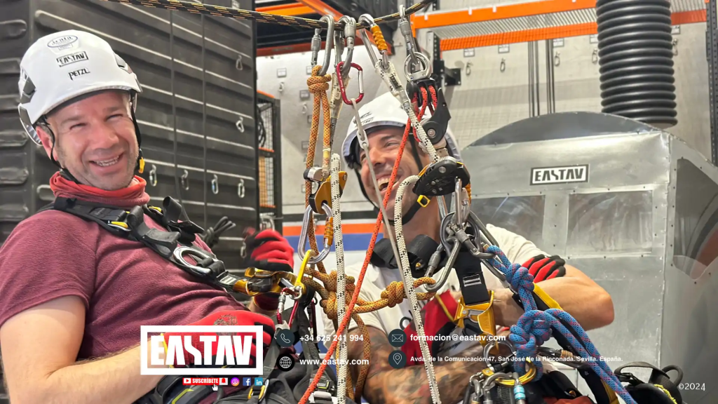 Dos trabajadores con equipo de seguridad eastav en instalación industrial con arneses.