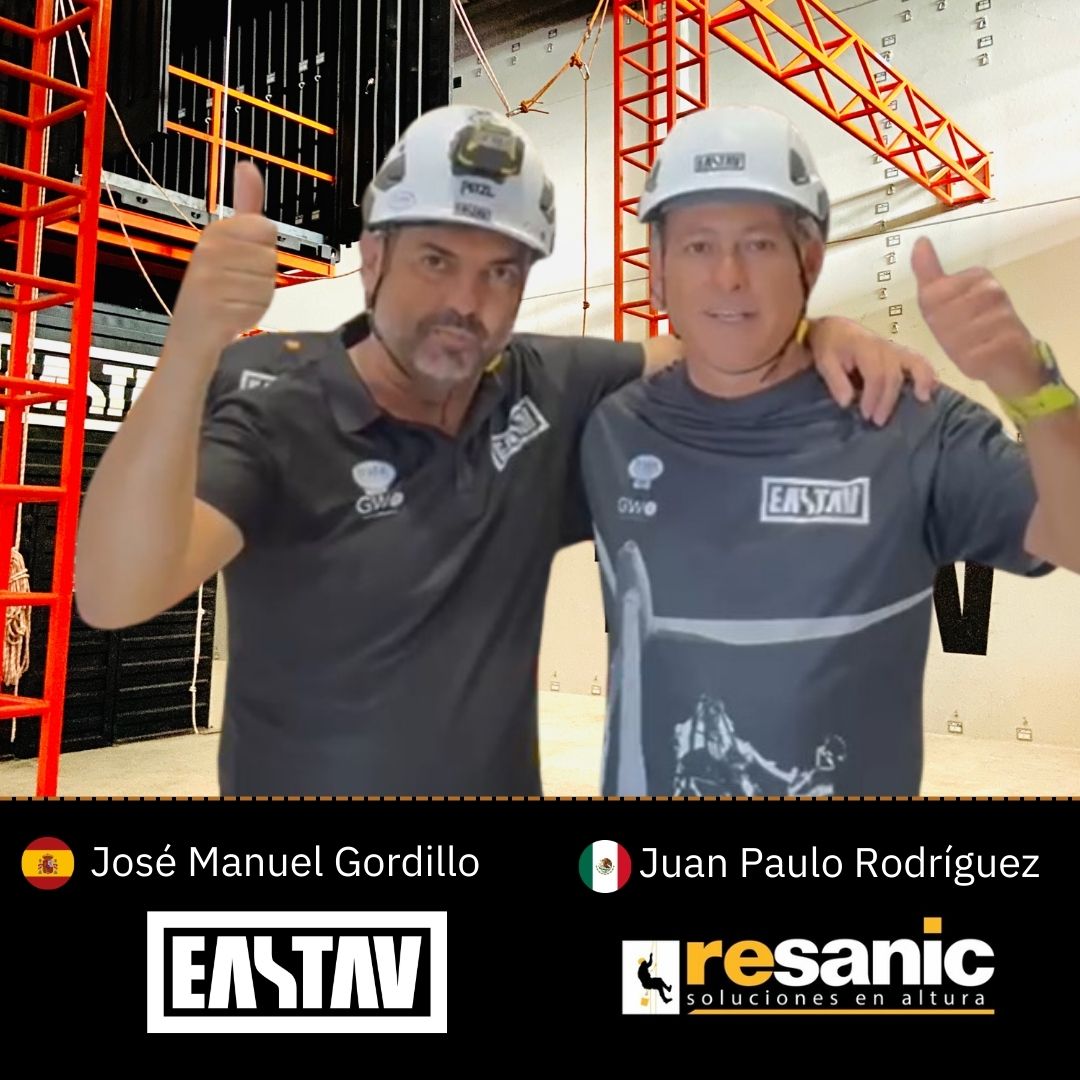 Dos trabajadores con cascos dando pulgar hacia arriba en sitio de construcción industrial.