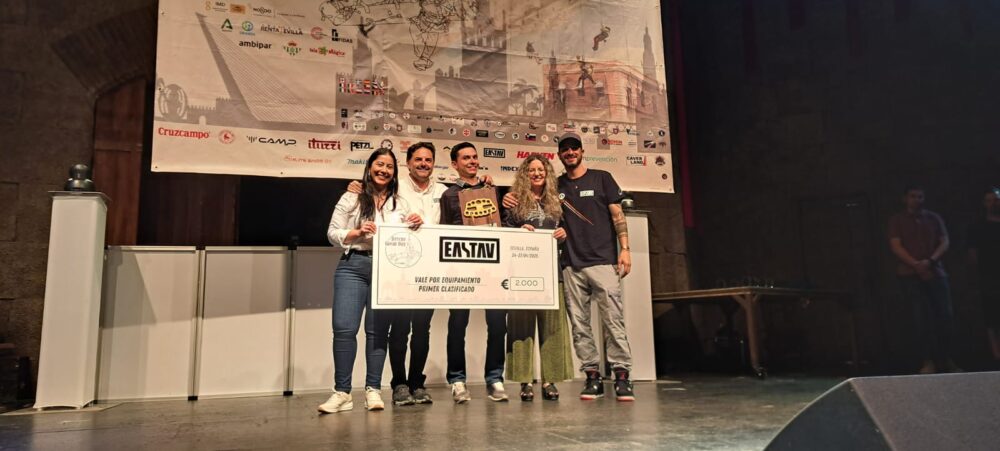 Cinco personas en un escenario sostienen un cheque de premio en una ceremonia de entrega de premios.
