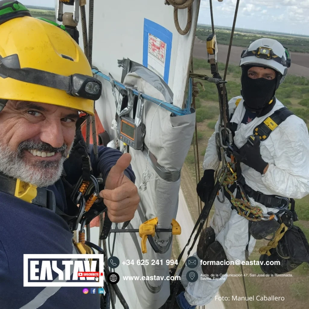 Two construction workers in safety harnesses and helmets on industrial tower platform