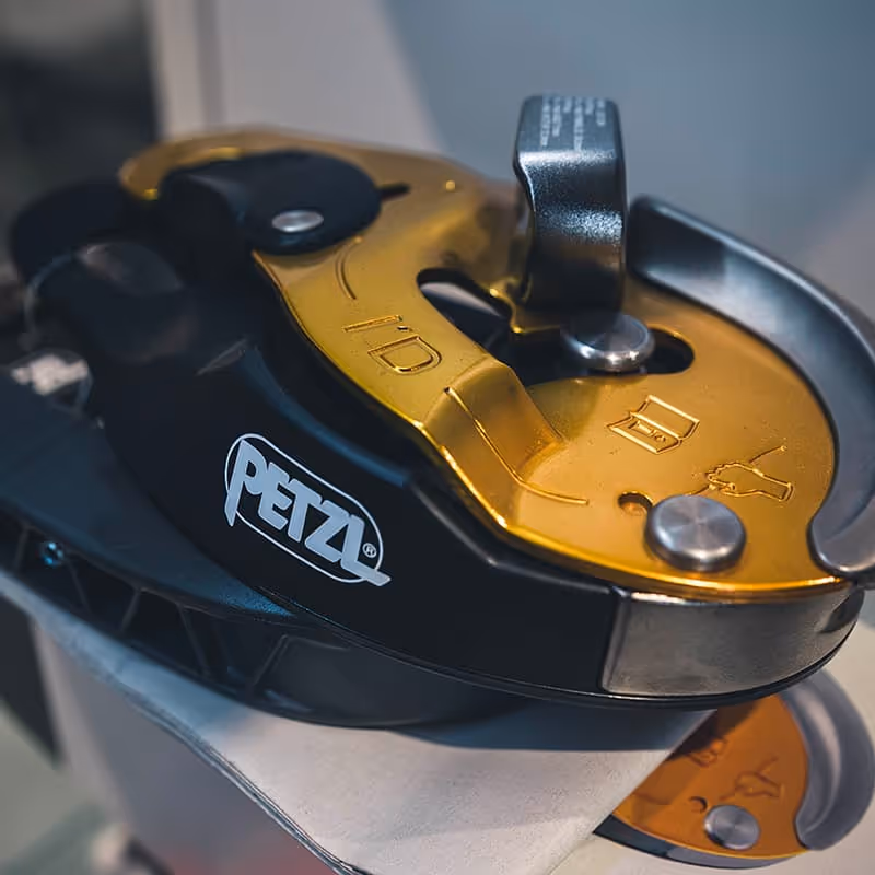 Poleas y accesorios de escalada Petzl con carabinas negras y doradas brillantes