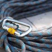 Carabiner de metal con cuerda azul y amarilla enrollada, equipo de escalada profesional.