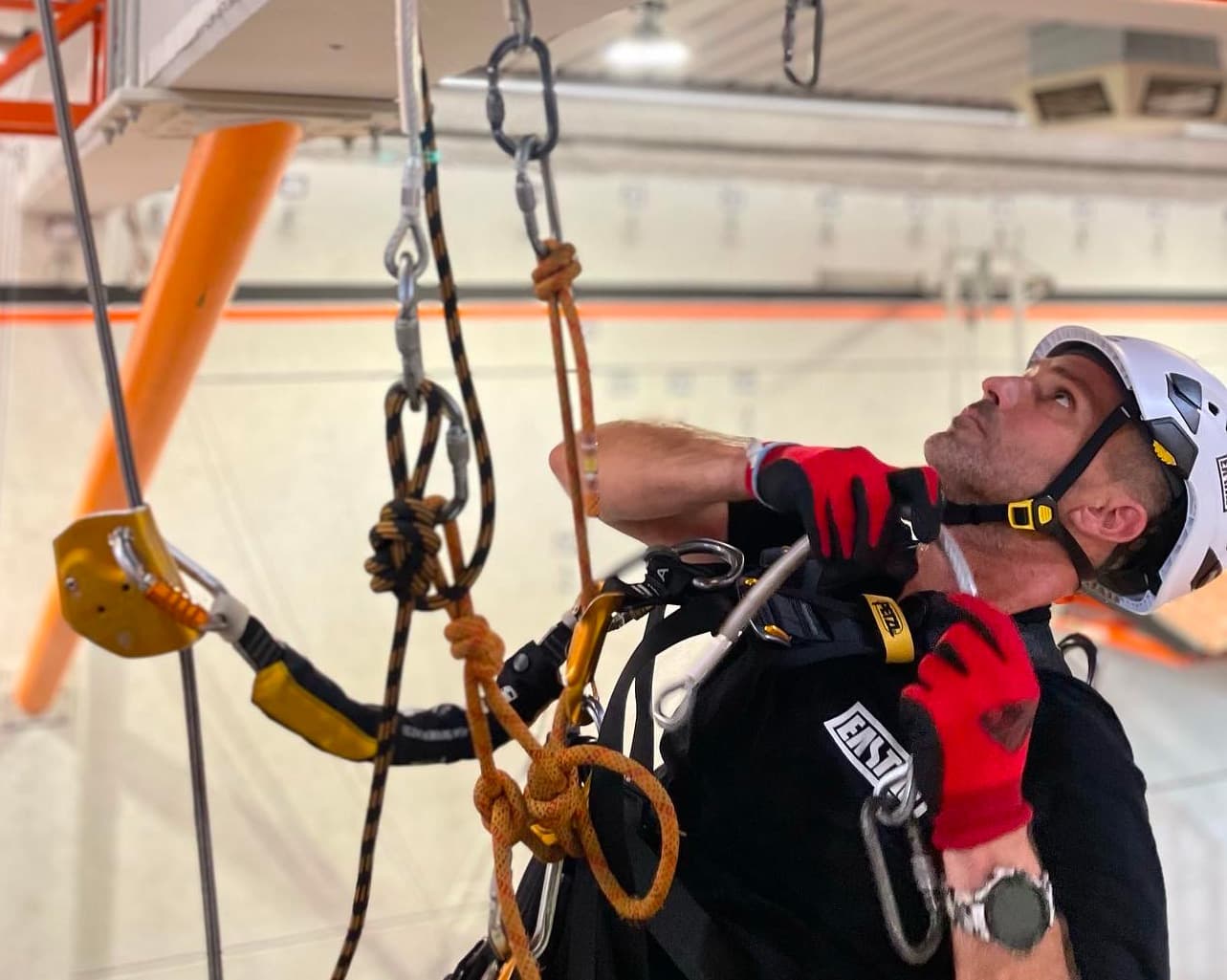 Profesional IRATA realizando trabajo en altura con equipos internacionales de seguridad y arnés de protección.