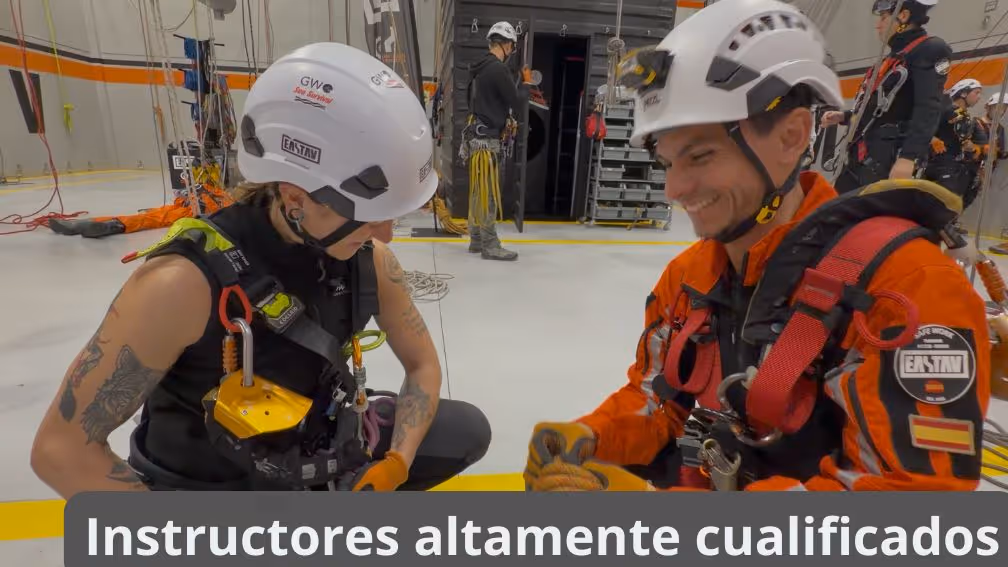 Two rescue workers in safety gear and white helmets inside an aircraft during training exercise.