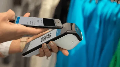 Person using a mobile phone to make a payment with QR code on a credit card machine