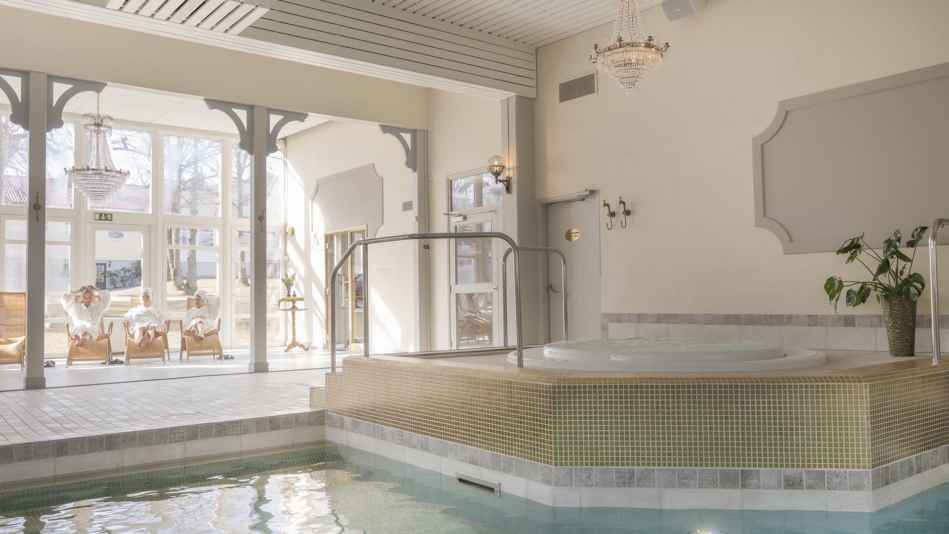 Lyxigt spa med pool och avslappningsområde i soligt rum.