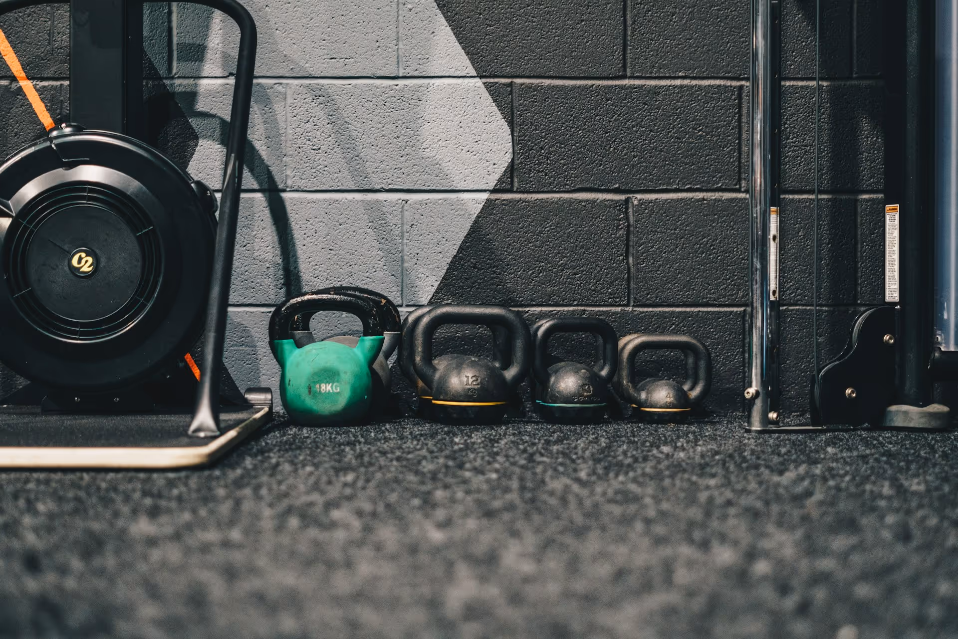 Kettlebells i gymmiljö på en matta framför en betongvägg.
