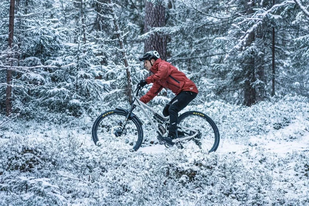 Person cyklar i snötäckt skog med mountainbike.