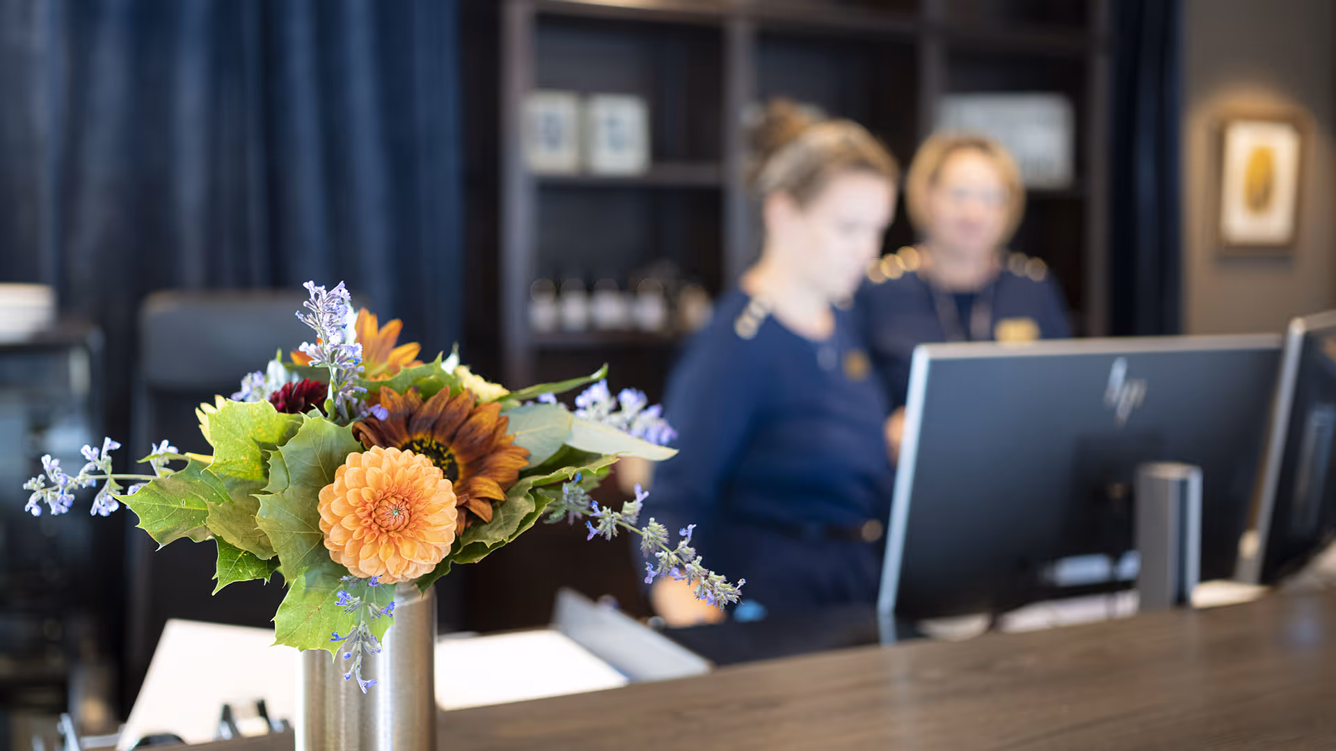Reception med blomsterarrangemang och receptionspersonal.