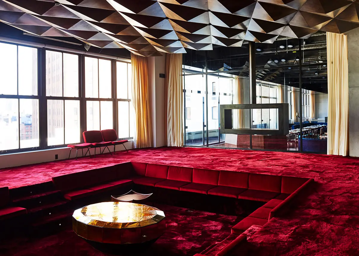 Bold interior at Spring Place featuring red lounge pit, geometric gold ceiling, and white drapes
