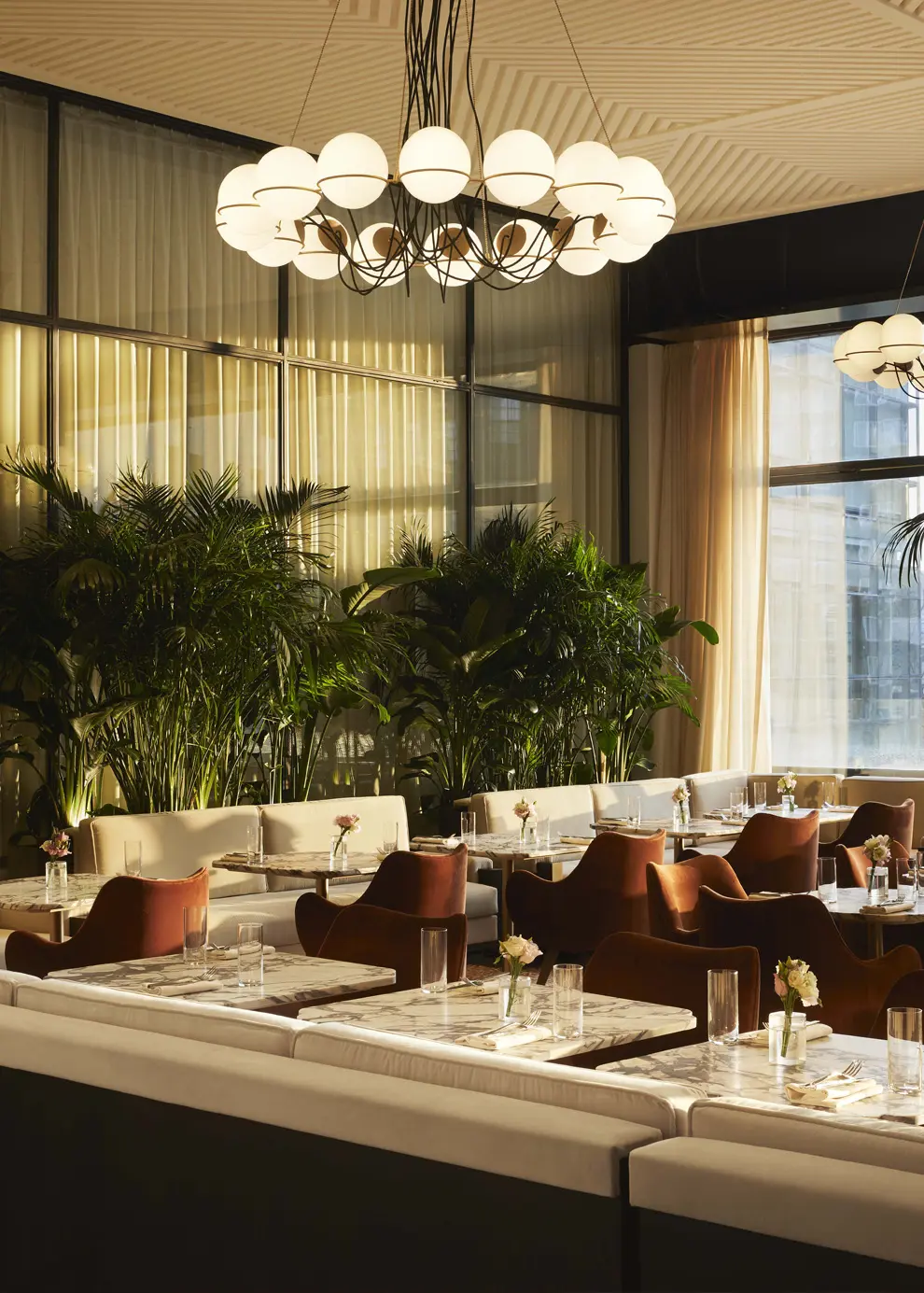 Spring Place dining area featuring cozy booths, greenery, and elegant globe lighting