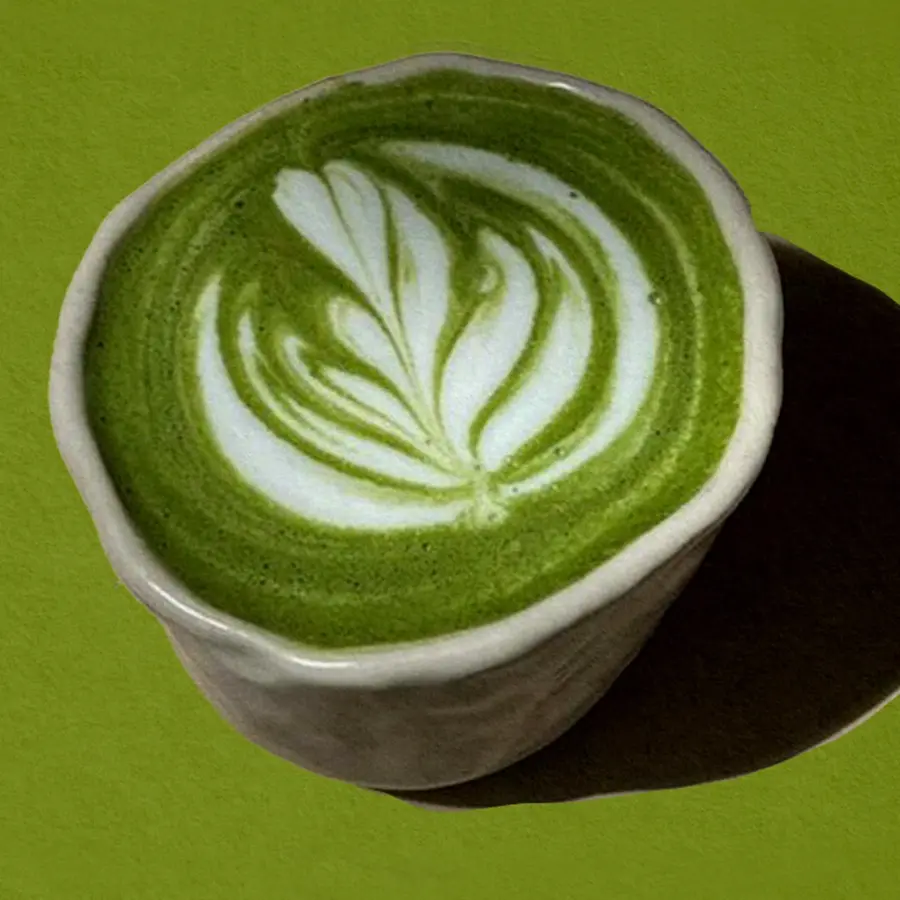 A cup of matcha latte against a green background