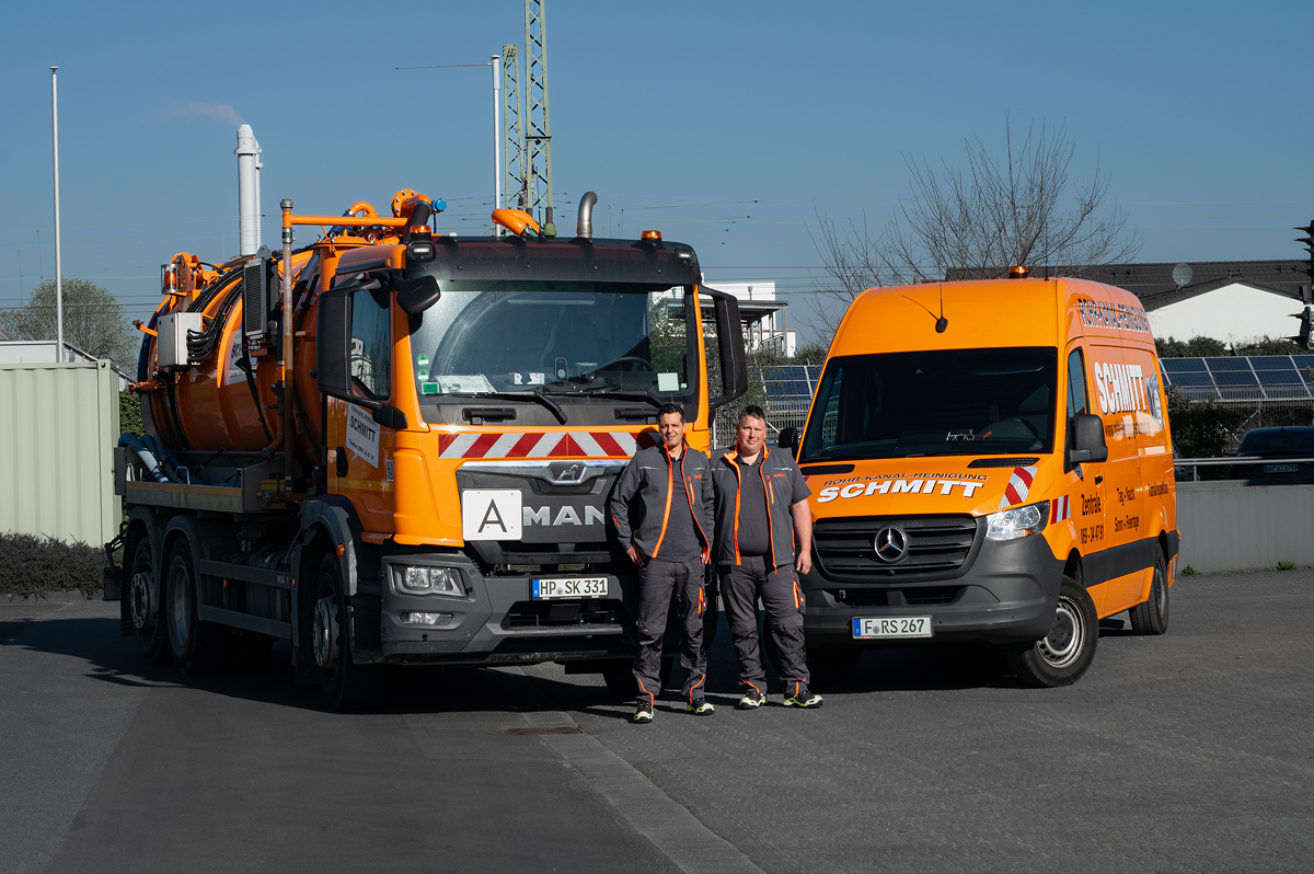 Zwei Menschen die vor zwei großen Fahrzeugen stehen