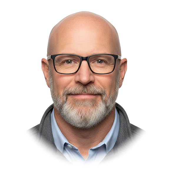 Portrait of a bald middle-aged man with glasses and a gray beard smiling, wearing a light blue shirt and gray jacket.