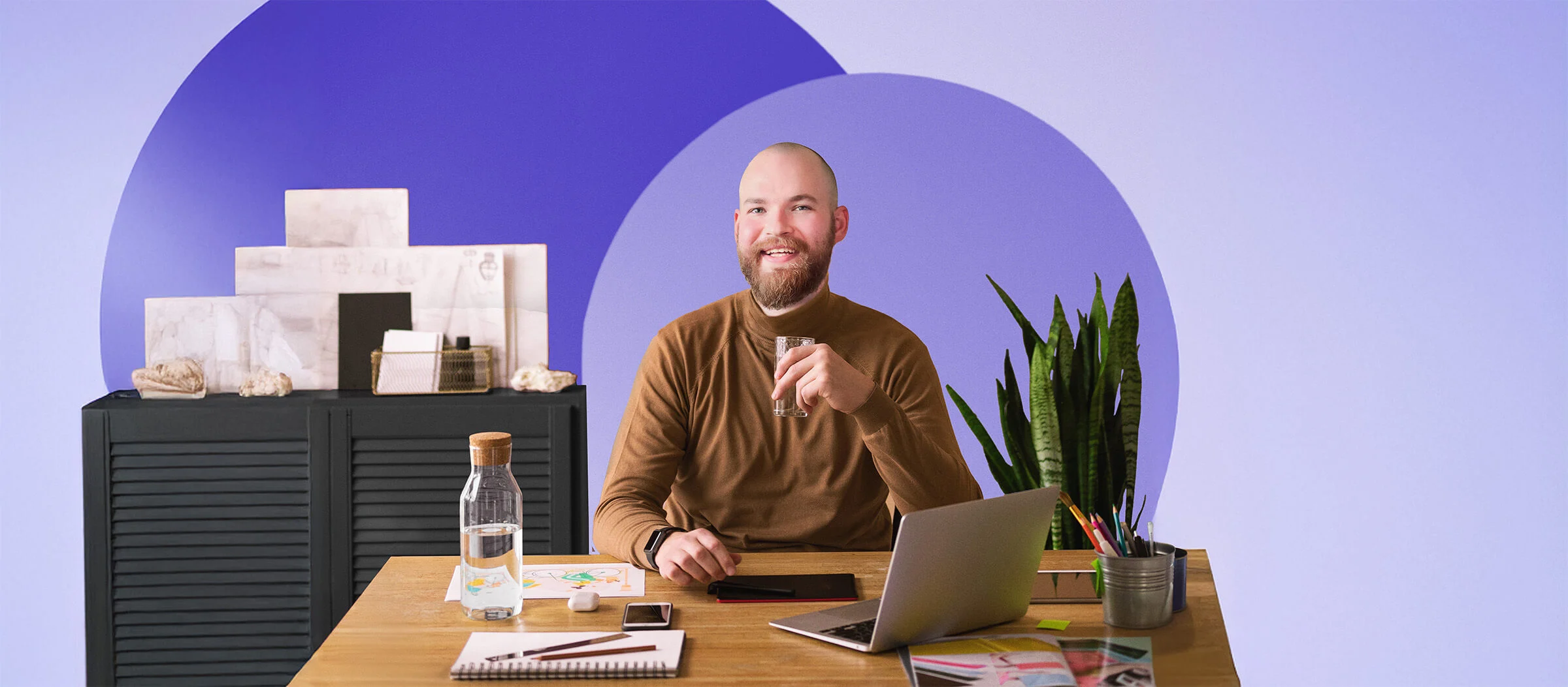 Man sitting in office with Ikea furniture and a purple background.